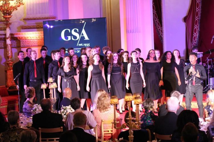 GSA Singers perform on stage in front of an audience seated at tables